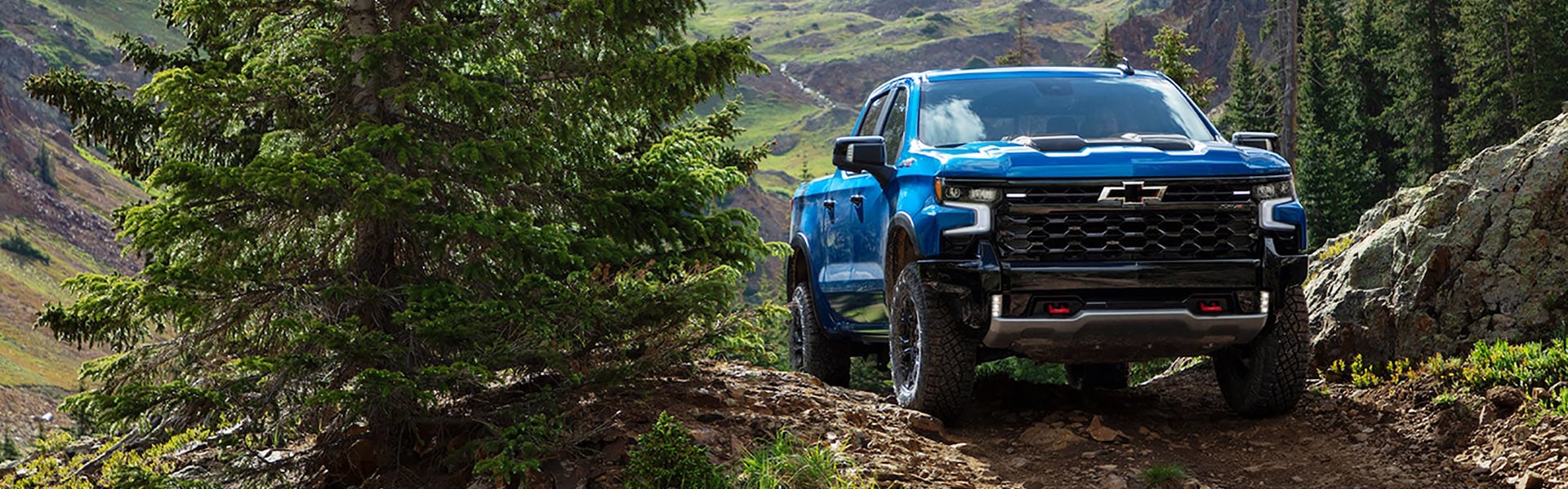Image of a blue 2022 Chevrolet Silverado 1500 parked on top of the mountain between trees
