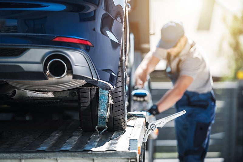 Photo of a mechanic mounting a car on a tow truck